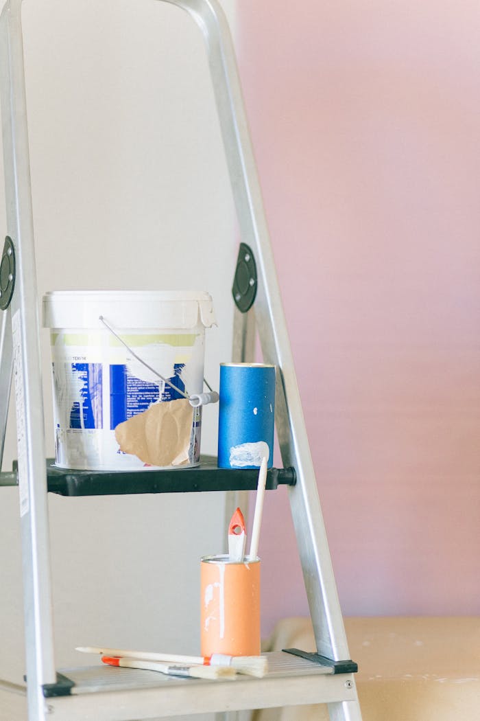 A ladder with painting tools and materials used for home renovation and interior design.